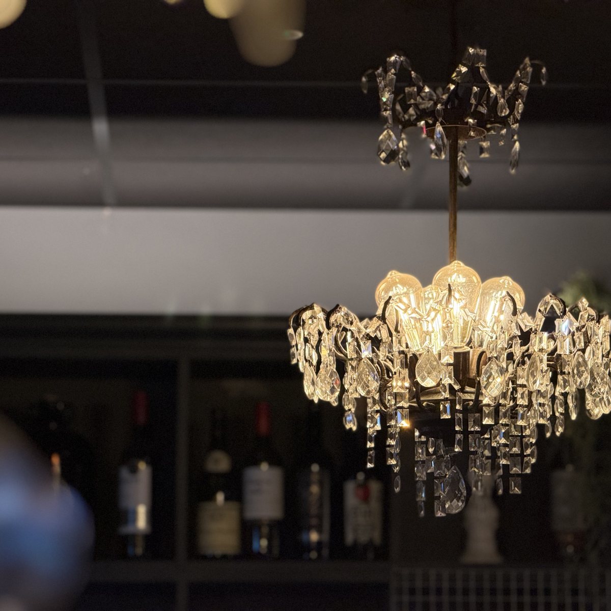 Crystal chandelier above the bar with bottle shelving behind